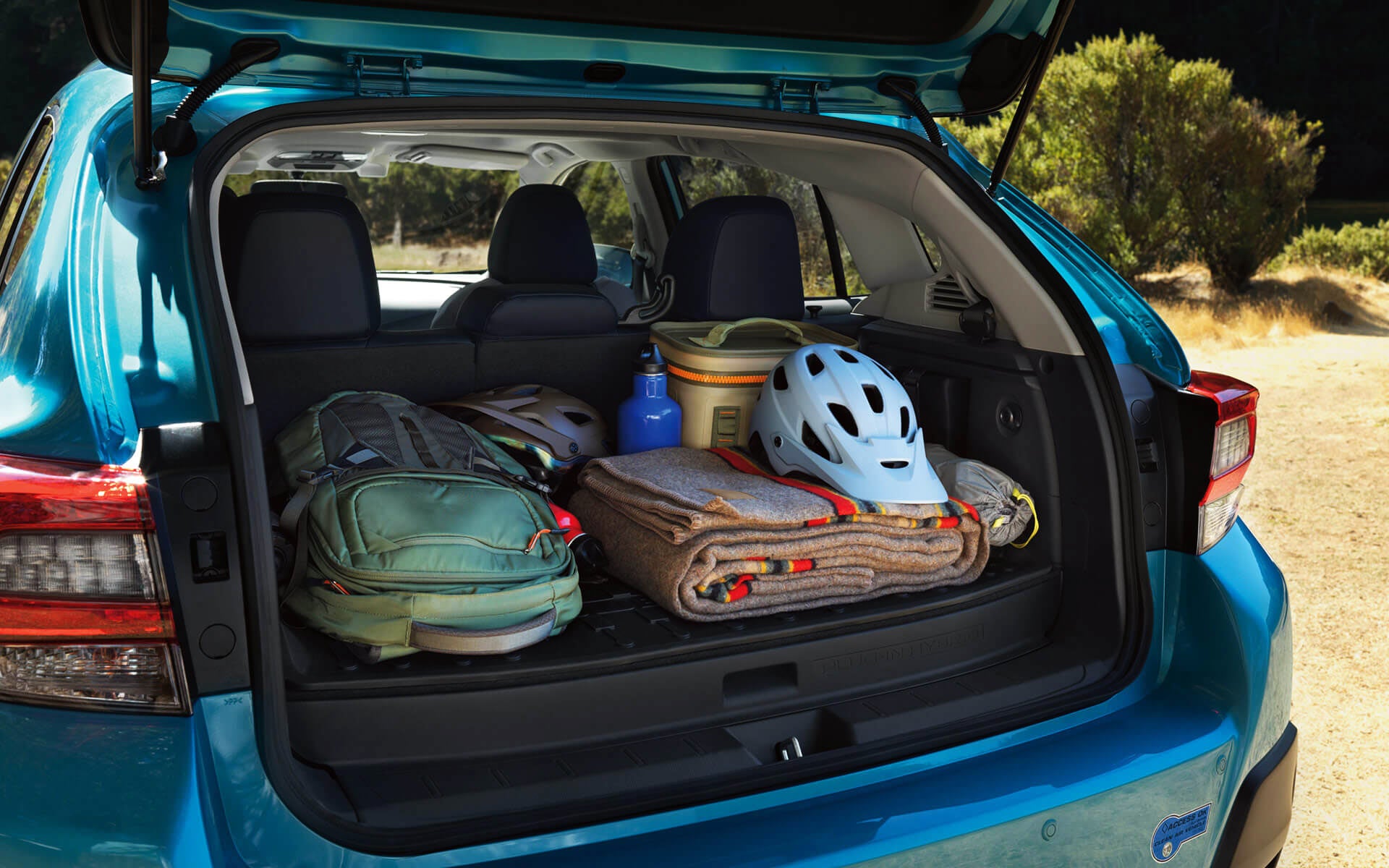 A backpack, blanket, and bike helmet in the rear cargo area of a Crosstrek Hybrid | Bergstrom Subaru Green Bay in Green Bay WI